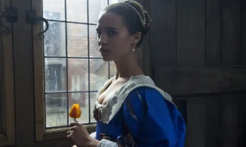Cena do filme Amor e Tulipas (2017) com Alicia Vikander segurando uma tulipa amarela enquanto olha pela janela em um ambiente com luz suave.