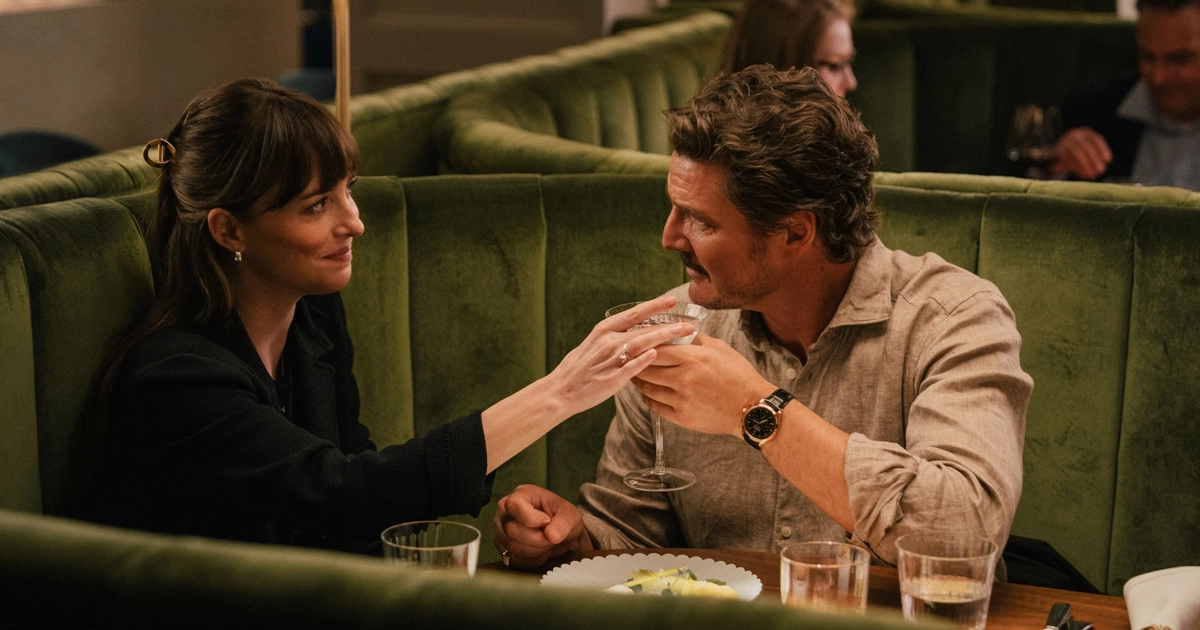 Cena do filme Materialists (2025) mostra Dakota Johnson e Pedro Pascal brindando em um restaurante elegante; à esquerda, Johnson sorri enquanto segura uma taça, e à direita, Pascal retribui o gesto com olhar carinhoso. Filme também conta com Chris Evans no elenco.