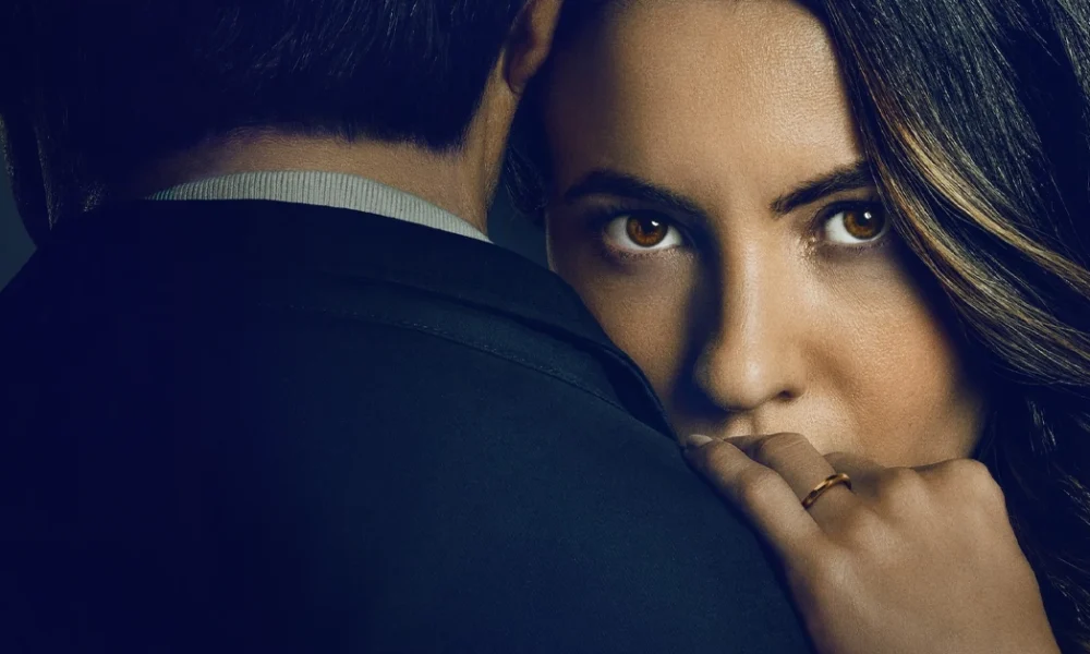 Imagem promocional do filme "O Jogo da Viúva" (2025), da Netflix, com Ivana Baquero encarando a câmera enquanto abraça o personagem de Tristán Ulloa.
