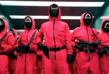 Guardiões mascarados de vermelho armados em cena de Round 6, série da Netflix.