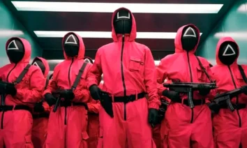 Guardiões mascarados de vermelho armados em cena de Round 6, série da Netflix.