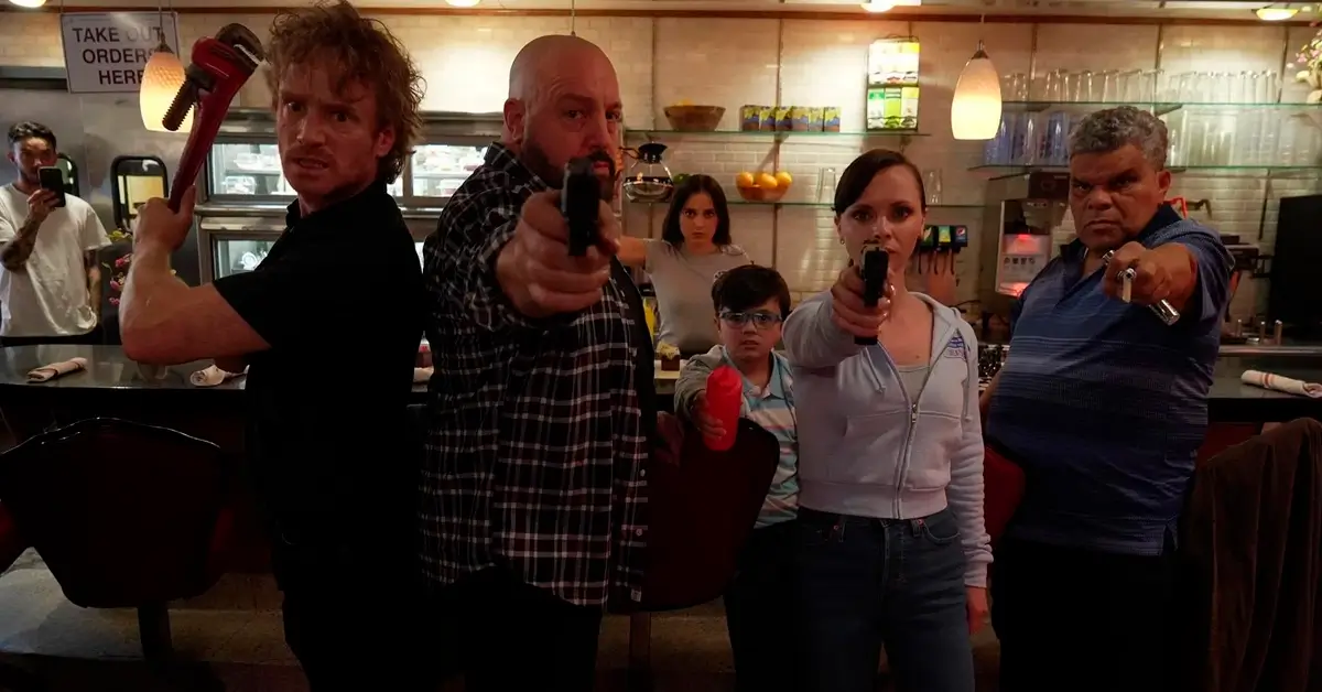 Cena intensa do filme Família à Prova de Balas com Kevin James, Christina Ricci e Luis Guzmán armados em uma lanchonete