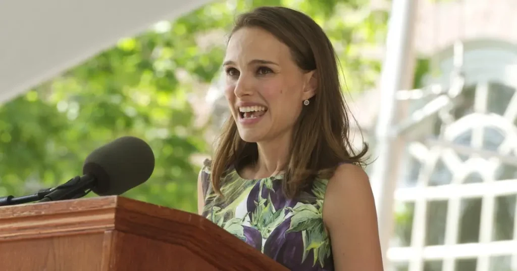 natalie portman harvard Natalie Portman discursando na formatura de Harvard em 2015, usando vestido floral e sorrindo no púlpito.