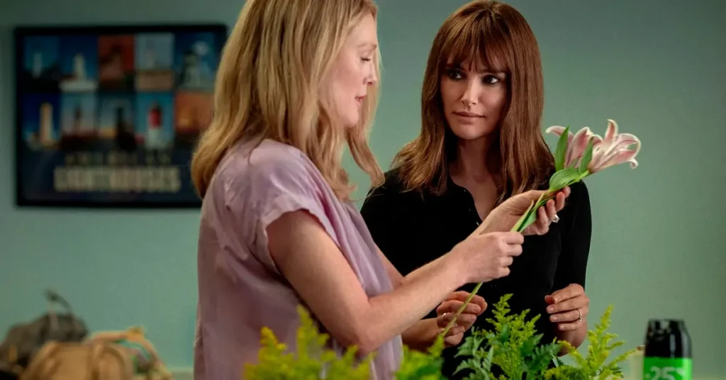 natalie portman segredos de um escandalo Cena do filme Segredos de um Escândalo (2023), com Julianne Moore e Natalie Portman segurando uma flor durante uma conversa;