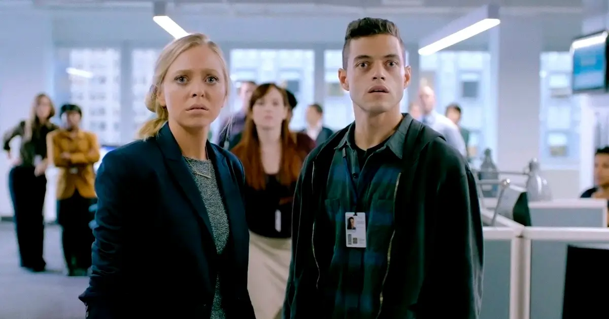 Angela Moss e Elliot Alderson na Allsafe Cybersecurity – Mr. Robot Angela Moss (Portia Doubleday) e Elliot Alderson (Rami Malek) em cena de Mr. Robot, trabalhando juntos na Allsafe Cybersecurity.