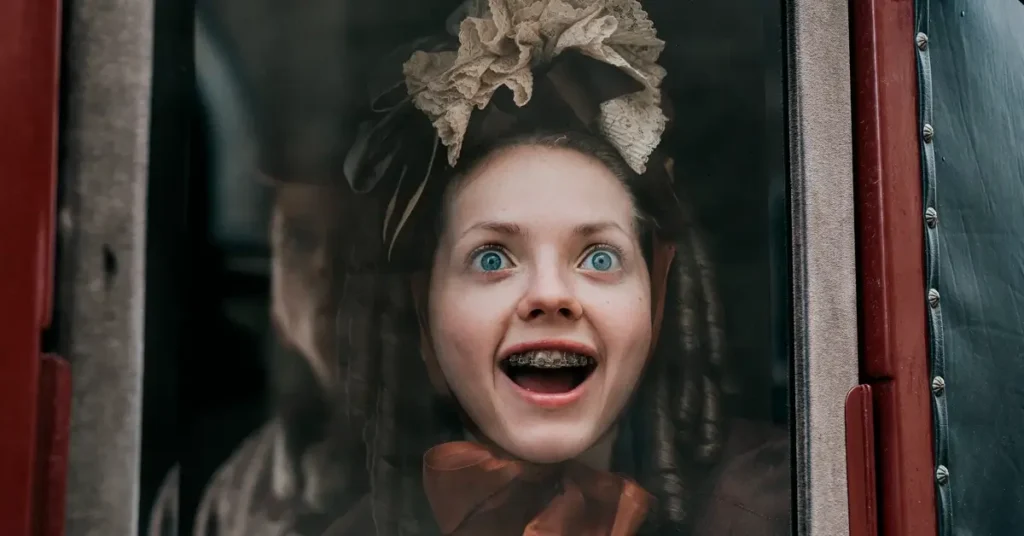 Personagem Elvira, interpretada por Lea Myren, sorrindo de forma inquietante em cena do filme The Ugly Stepsister (2025)