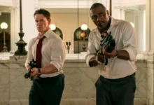John Cena como Will Derringer e Idris Elba como Sam Clarke armados em cena de ação do filme Chefes de Estado (Heads of State), estreia em 2 de julho de 2025 no Prime Video.