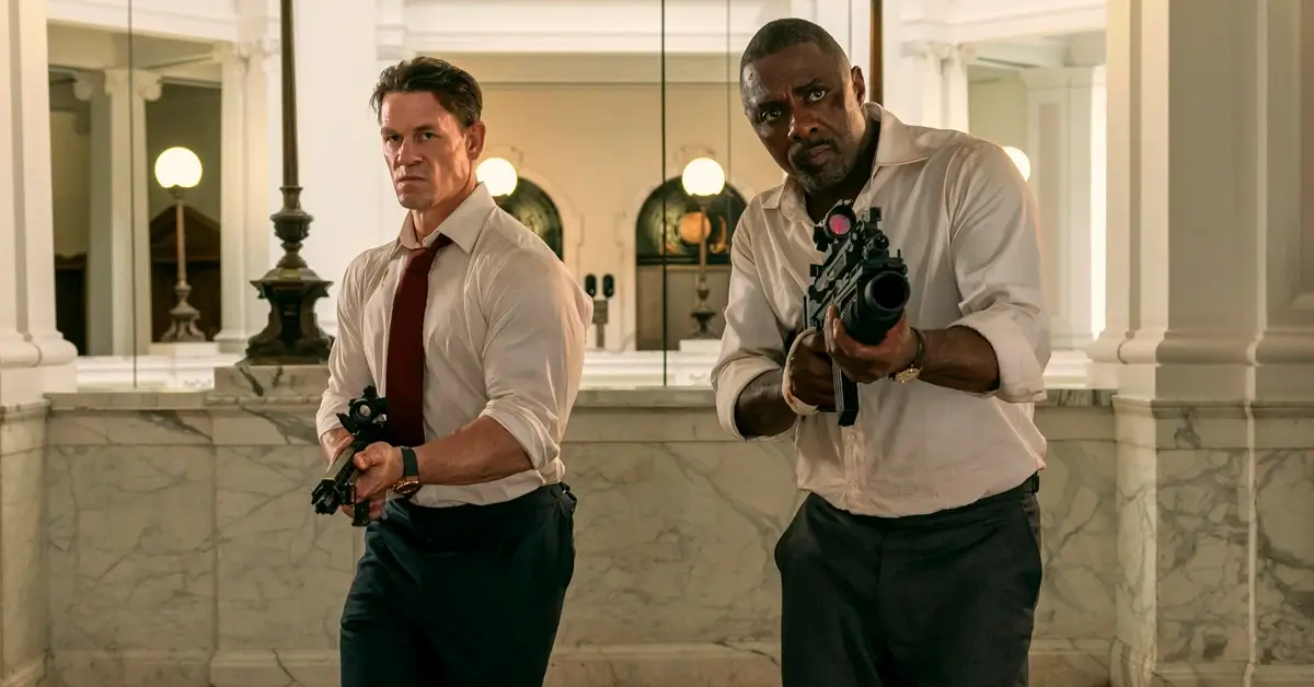 John Cena como Will Derringer e Idris Elba como Sam Clarke armados em cena de ação do filme Chefes de Estado (Heads of State), estreia em 2 de julho de 2025 no Prime Video.