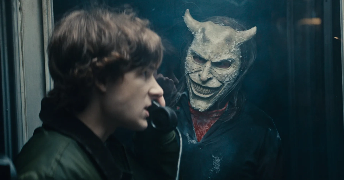 Cena do trailer de O Telefone Preto 2 mostra Finney (Mason Thames) em uma cabine telefônica, observado pelo sinistro vilão interpretado por Ethan Hawke, usando uma máscara demoníaca.