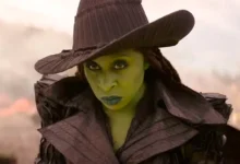 Elphaba com expressão séria e chapéu pontudo em cena de Wicked: Parte 2 (2025), interpretada por Cynthia Erivo.