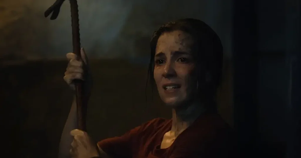 Marjorie Estiano com rosto sujo e expressão de pânico segurando um pé de cabra no filme Abraço de Mãe (2024).