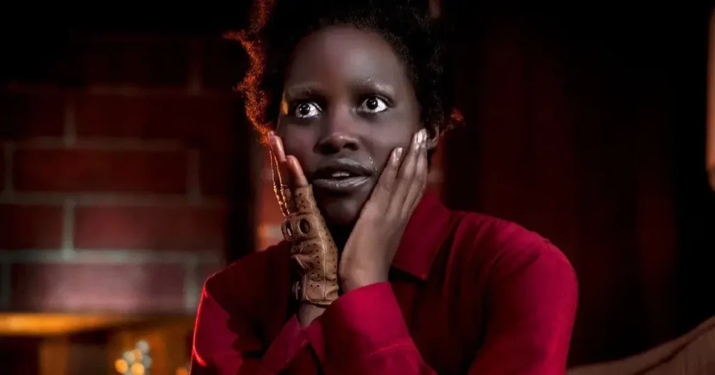 Lupita Nyong'o com expressão assustada e maquiagem em cena do filme de terror Nós (2019).