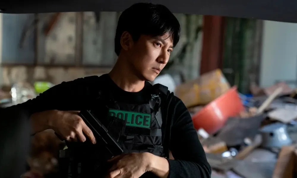 Kim Nam-gil armado e usando colete policial em cena da série sul-coreana Gatilho (Teurigeo), da Netflix