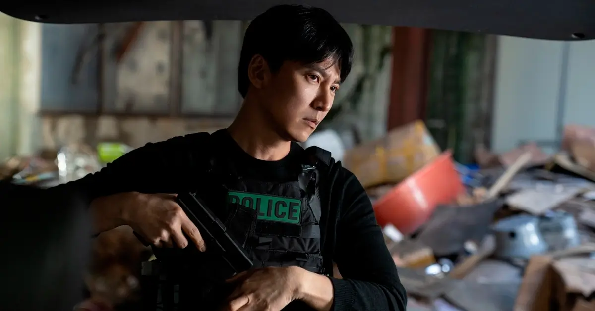 Kim Nam-gil armado e usando colete policial em cena da série sul-coreana Gatilho (Teurigeo), da Netflix