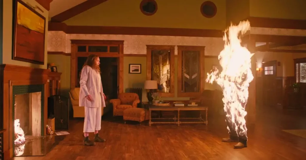 hereditario 2018 cena combustao espontanea Cena de Hereditário (2018) mostrando Annie Graham observando Peter em combustão espontânea na sala de estar da casa Graham