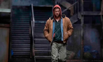 Glen Powell caminha em cena do filme O Concorrente (2025)