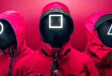 Guardas mascarados com símbolos de círculo, quadrado e triângulo em trajes vermelhos na série Round 6 da Netflix