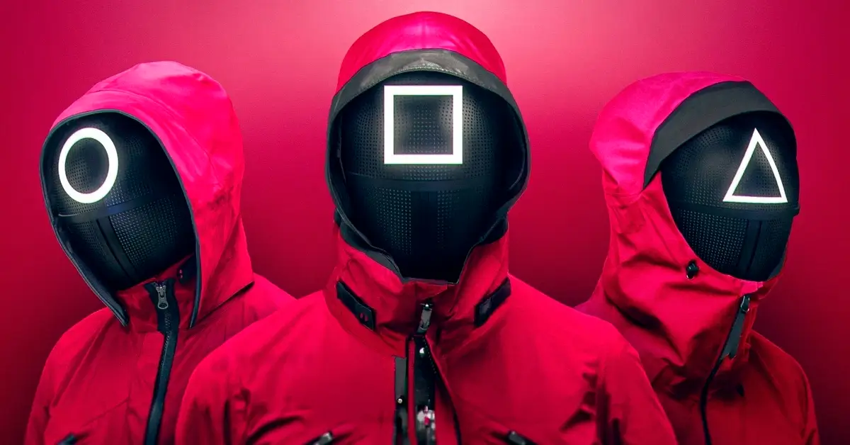 Guardas mascarados com símbolos de círculo, quadrado e triângulo em trajes vermelhos na série Round 6 da Netflix