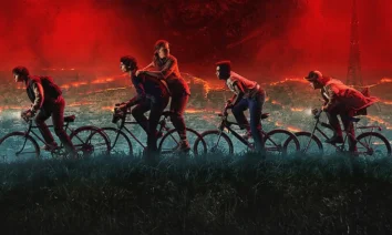 Elenco principal de Stranger Things 5 pedalando rumo ao caos, com o céu vermelho do Mundo Invertido ao fundo.