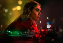 Vanessa Kirby em cena do filme A Noite Sempre Chega (2025) da Netflix, olhando pensativa com luzes coloridas de neon ao fundo