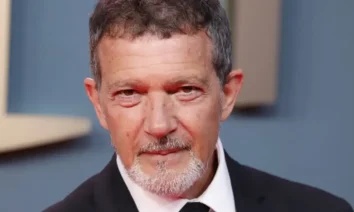 Antonio Banderas aos 65 anos em evento oficial, usando smoking preto e gravata, sorrindo para fotógrafos em tapete vermelho