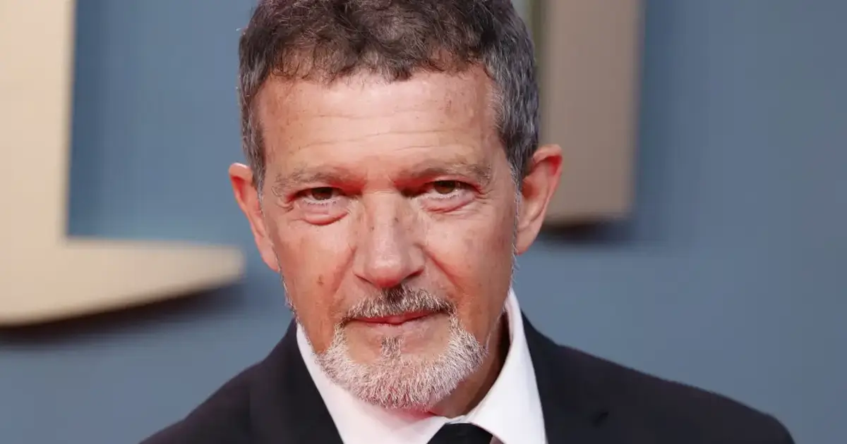 Antonio Banderas aos 65 anos em evento oficial, usando smoking preto e gravata, sorrindo para fotógrafos em tapete vermelho