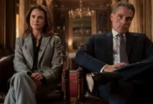 Keri Russell e Rufus Sewell sentados em poltronas formais em cena da terceira temporada de A Diplomata.