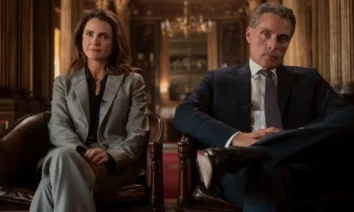 Keri Russell e Rufus Sewell sentados em poltronas formais em cena da terceira temporada de A Diplomata.