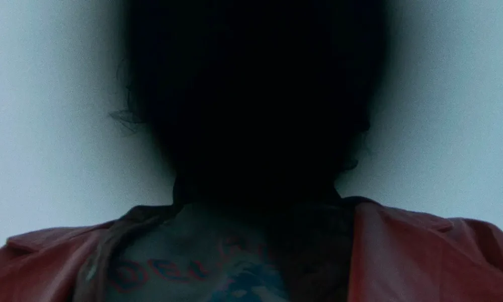 Silhueta sombria de um personagem com jaqueta vermelha em cena enigmática do filme "Para Sempre Minha" (Keeper), dirigido por Osgood Perkins.