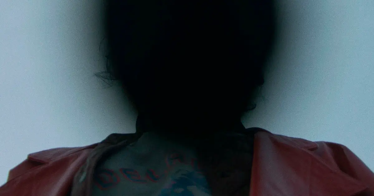 Silhueta sombria de um personagem com jaqueta vermelha em cena enigmática do filme "Para Sempre Minha" (Keeper), dirigido por Osgood Perkins.