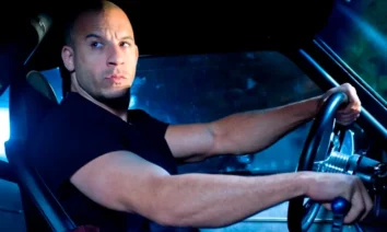Vin Diesel dirigindo carro esportivo em cena noturna do filme Velozes e Furiosos 4 com iluminação azul