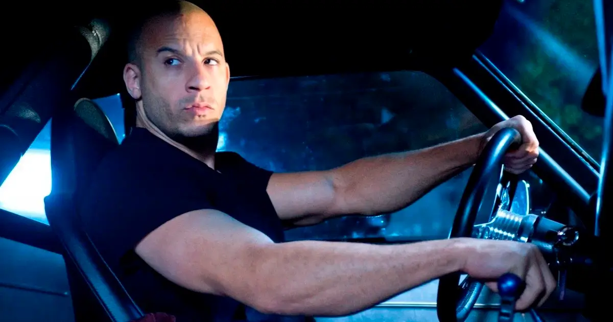 Vin Diesel dirigindo carro esportivo em cena noturna do filme Velozes e Furiosos 4 com iluminação azul