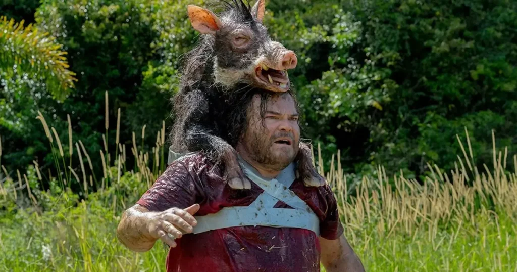 Jack Black em cena do trailer de Anaconda (2025), usando a cabeça de um javali como disfarce na selva.