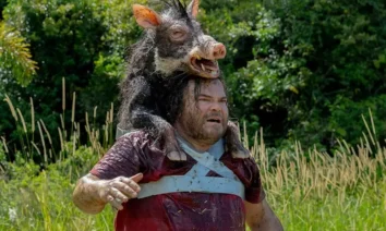 Jack Black em cena do trailer de Anaconda (2025), usando a cabeça de um javali como disfarce na selva.