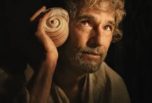Rodrigo Santoro segura uma concha e observa o horizonte em cena de O Filho de Mil Homens, novo filme da Netflix dirigido por Daniel Rezende.