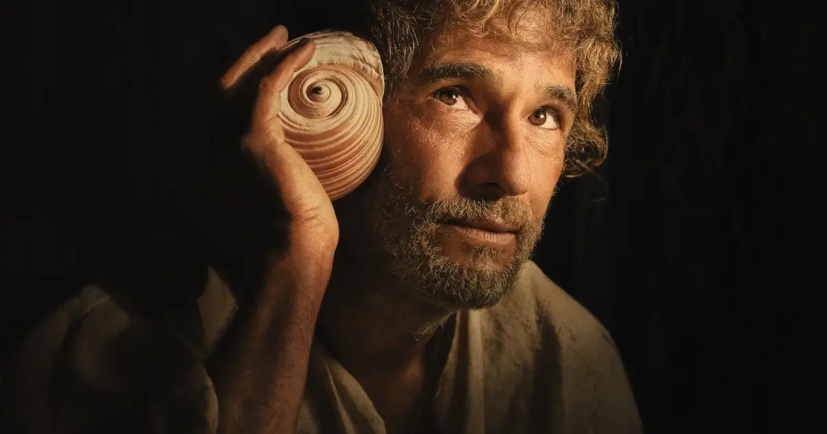 Rodrigo Santoro segura uma concha e observa o horizonte em cena de O Filho de Mil Homens, novo filme da Netflix dirigido por Daniel Rezende.