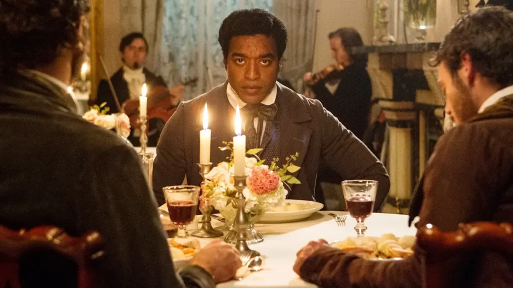 12 anos de escravidao 2013 filme Chiwetel Ejiofor como Solomon Northup sentado à mesa de jantar em cena de 12 Anos de Escravidão
