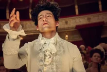 amadeus serie 2025 Will Sharpe como Wolfgang Amadeus Mozart na série Amadeus da Sky TV, vestindo traje de época branco ornamentado do século XVIII em teatro