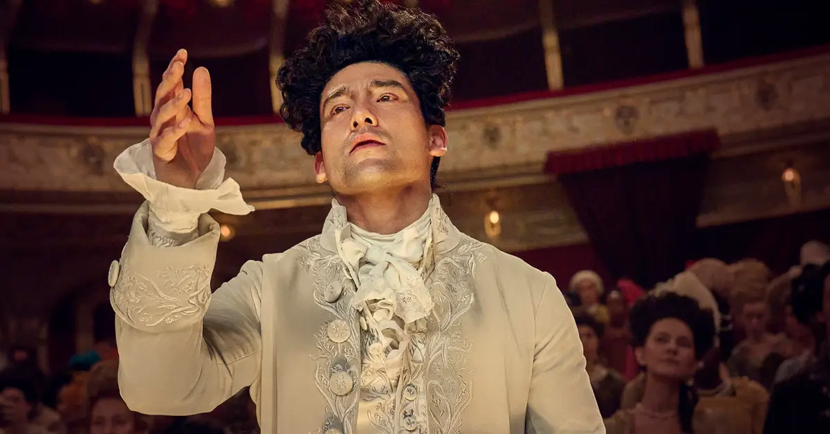 Will Sharpe como Wolfgang Amadeus Mozart na série Amadeus da Sky TV, vestindo traje de época branco ornamentado do século XVIII em teatro