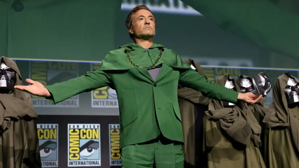 Robert Downey Jr usando capa e capuz verde do Doutor Destino na Comic-Con anunciando Vingadores Doomsday, filme da Marvel em 2026