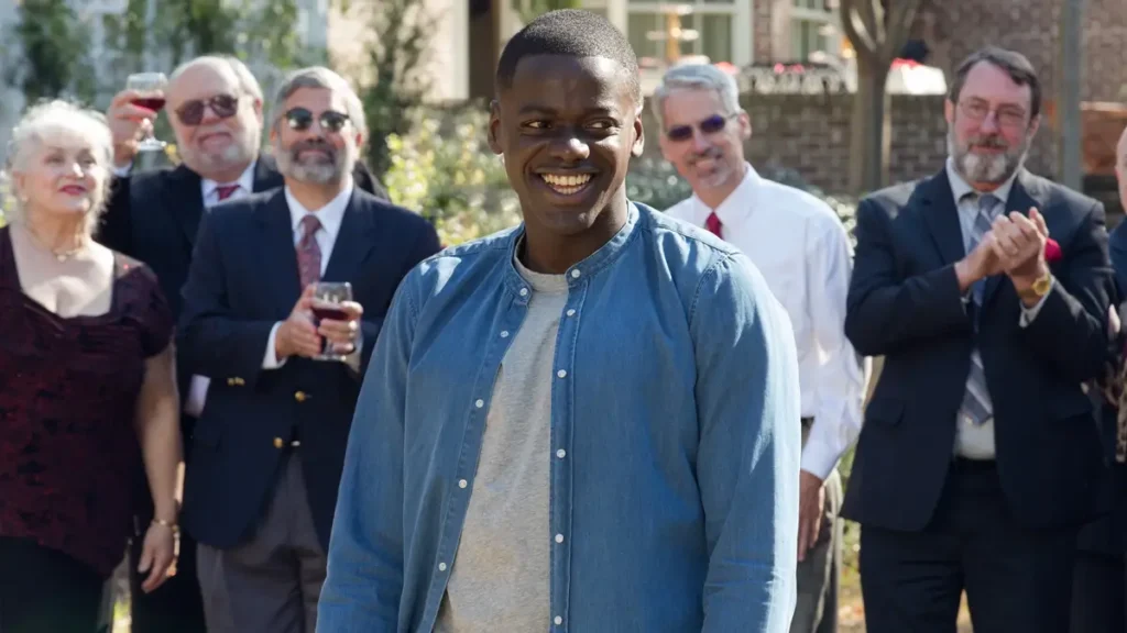 corra get out 2017 filme Daniel Kaluuya sorrindo em cena de Corra! cercado por pessoas brancas em festa ao ar livre