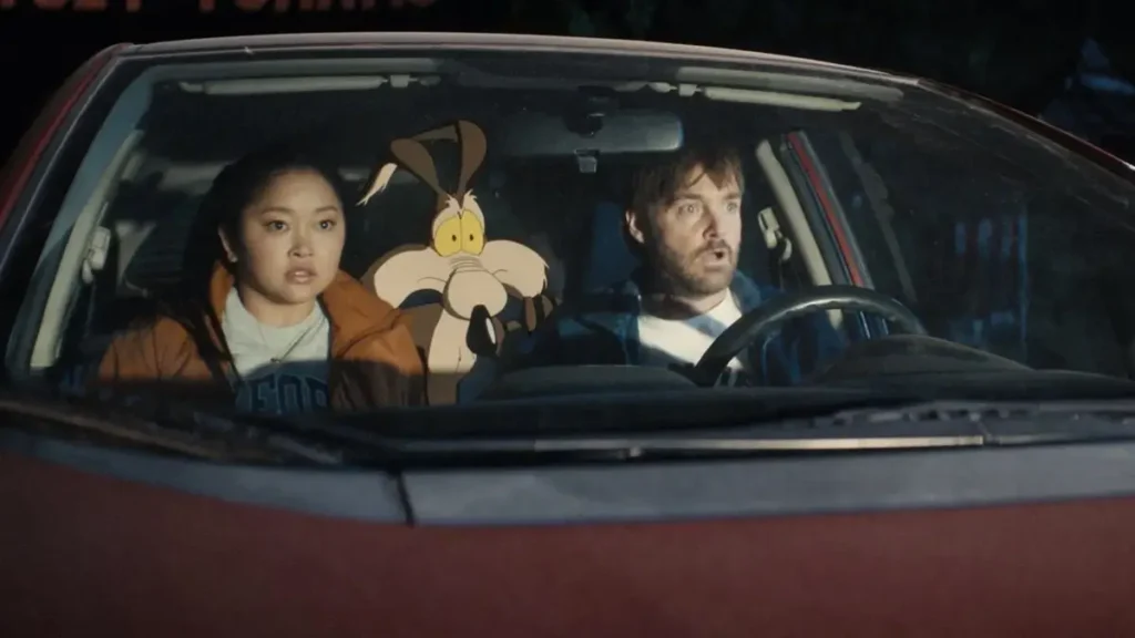 Will Forte e Lana Condor dentro de carro com Coiote Wile E no banco traseiro em Coyote vs Acme, um dos filmes da Warner em 2026