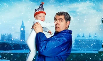 Rowan Atkinson segura um bebê em cena divertida da série Homem x Bebê, da Netflix.