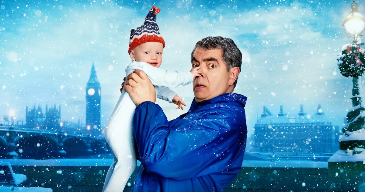Rowan Atkinson segura um bebê em cena divertida da série Homem x Bebê, da Netflix.