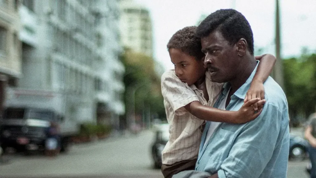 marighella 2021 filme Seu Jorge como Carlos Marighella carregando criança em cena de Marighella nas ruas