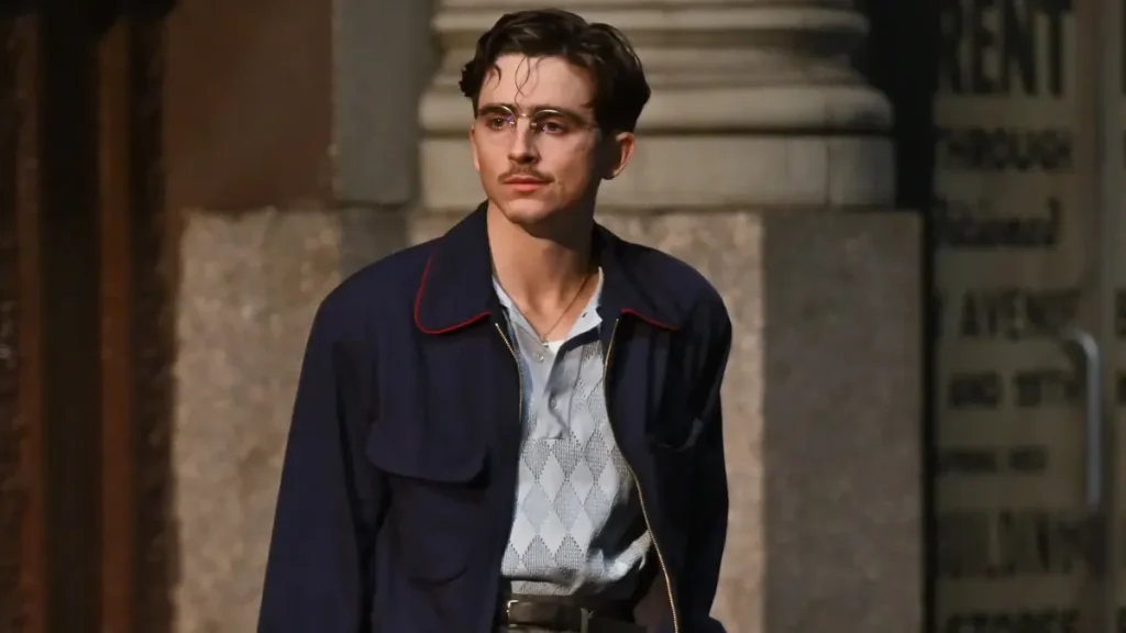 Timothée Chalamet usando jaqueta azul marinho em cena de Marty Supreme, filme baseado na história real do campeão de tênis de mesa Marty Reisman, entre os filmes 2026 no Brasil