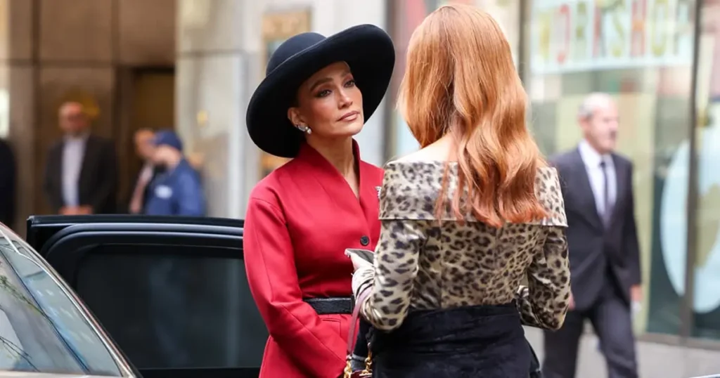 Jennifer Lopez nos bastidores de A Última Sra. Parrish vestindo blazer vermelho e chapéu preto em cena urbana elegante, thriller entre os lançamentos da Netflix em 2026