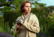 Mia McKenna-Bruce segura um relógio antigo no jardim em cena da série Os Sete Relógios de Agatha Christie, produção original da Netflix.