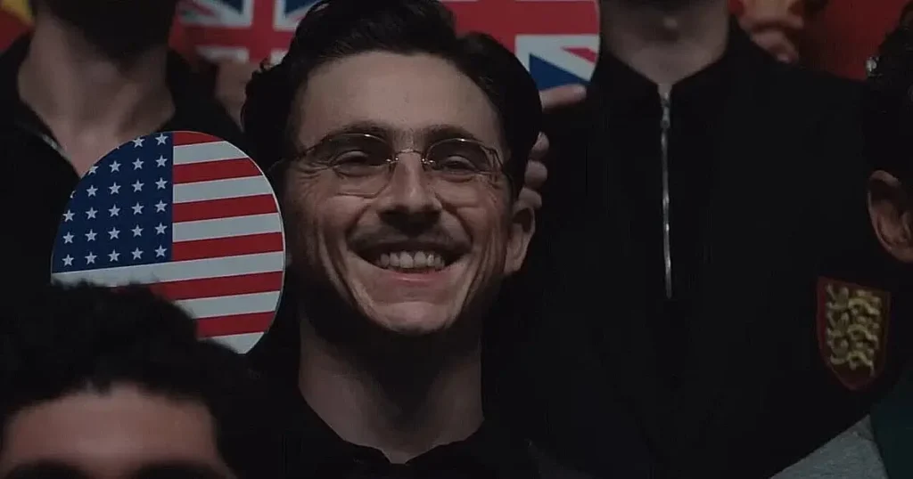 oscar 2026 marty supreme Timothée Chalamet usando óculos vintage e sorrindo em Marty Supreme, drama esportivo de Josh Safdie ambientado na Nova York dos anos 1950, candidato ao Oscar 2026