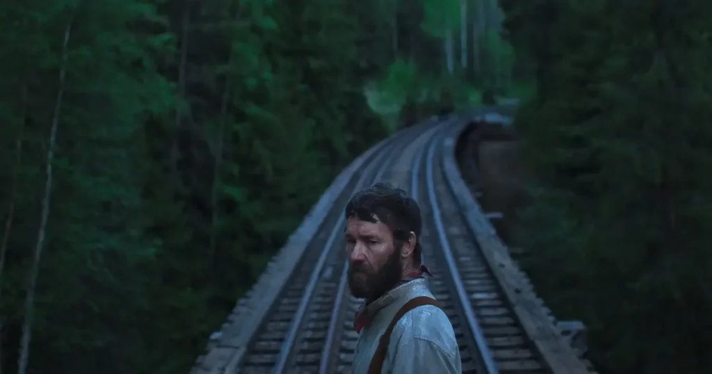 oscar 2026 sonhos de trem Joel Edgerton em Sonhos de Trem (2025), drama da Netflix cotado como possível aposta ao Oscar 2026, em cena sobre trilhos cercados por floresta verde.